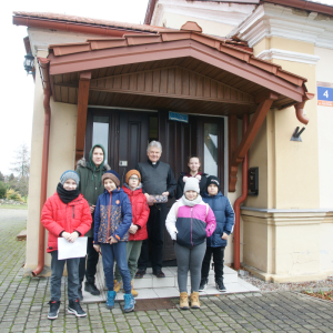 Grupa uczestników wraz z Księdzem Proboszczem, stojący przed budynkiem plebanii.