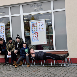 Grupa uczestników gry terenowej, stojąca przed Marketem "Zosia".